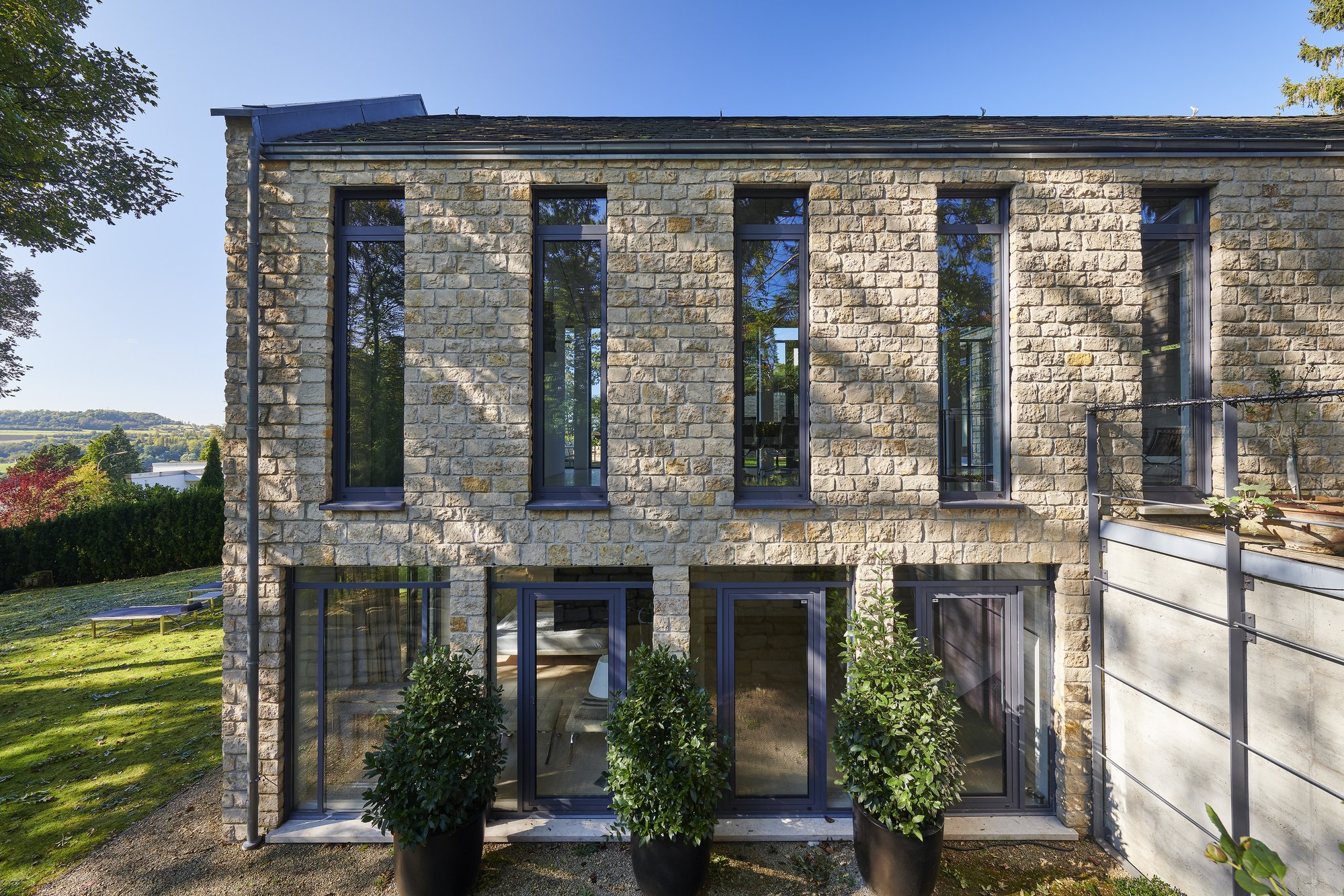 Haus S., Bliesgau, Saarland — Die zweigeschossige Pfeilerfassade mit schmalen Stahlfenstern