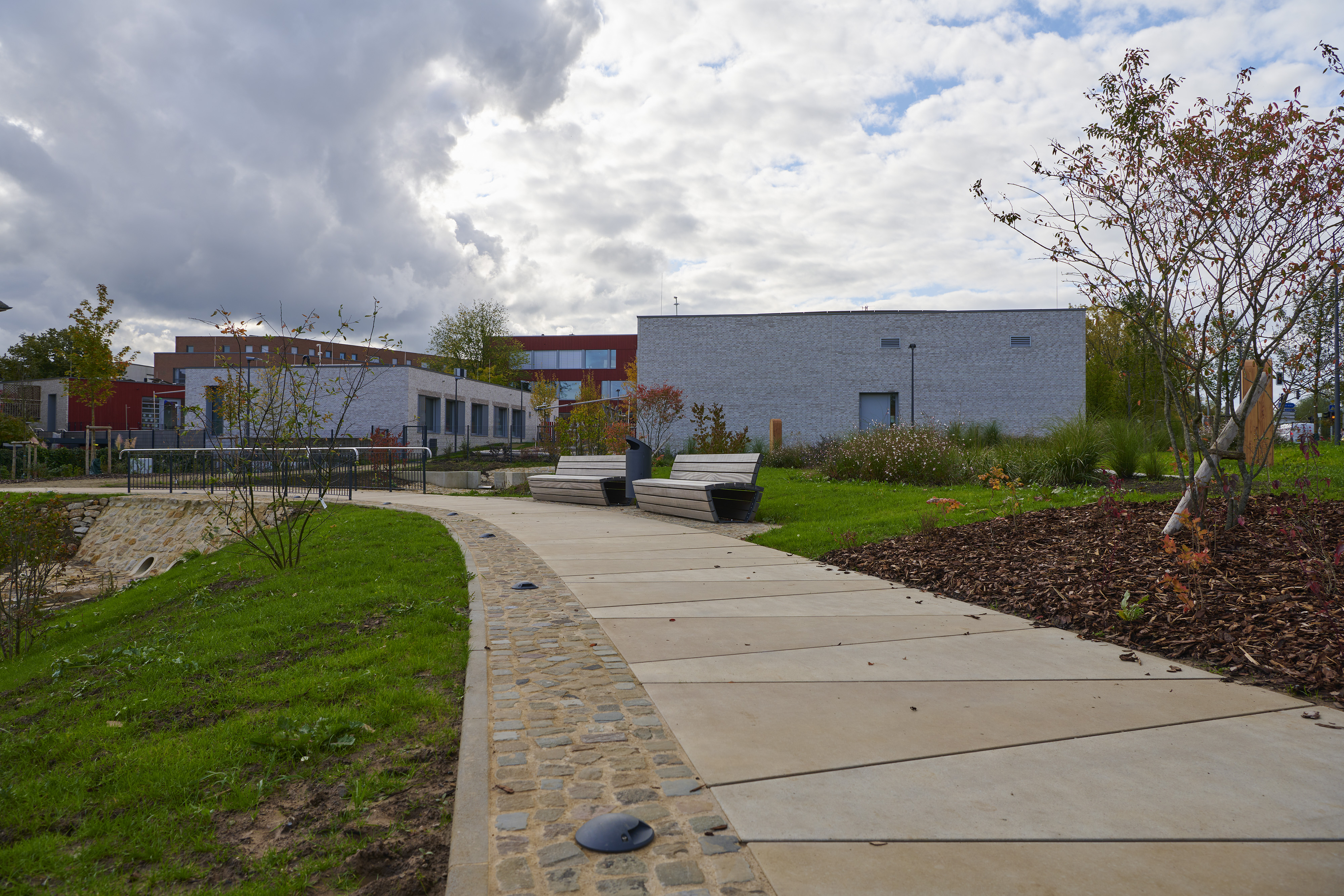 Fotografien Schulkomplex mit Kita und Retentionspark Wobrécken, Esch an der Alzette — Der Rundweg um die Retensionsfläche ist mit Punktleuchten im Boden versehen.