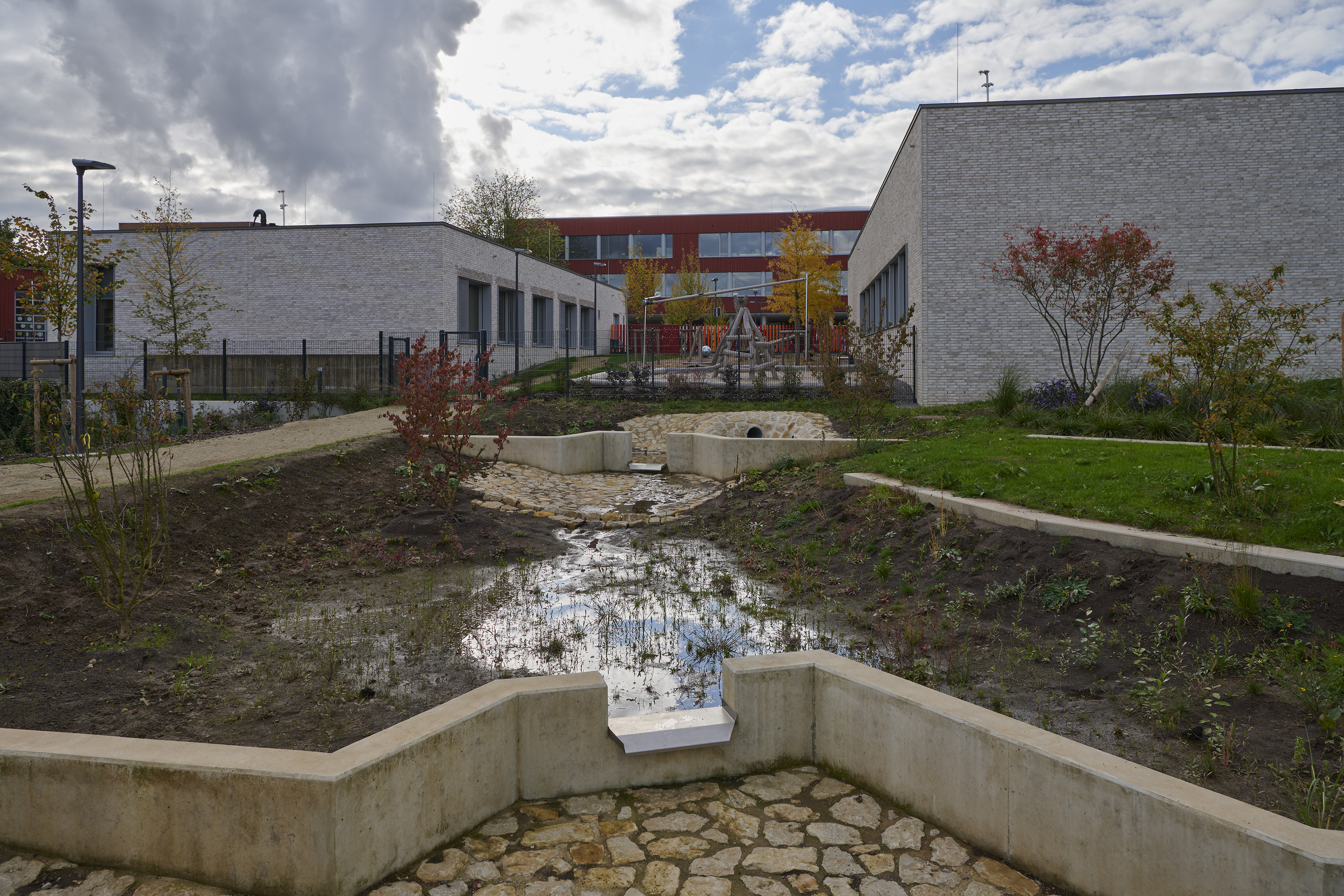 Fotografien Schulkomplex mit Kita und Retentionspark Wobrécken, Esch an der Alzette — Über die Wassertreppe wird das anfallende Niederschlagwasser in den Retensionspark abgeleitet