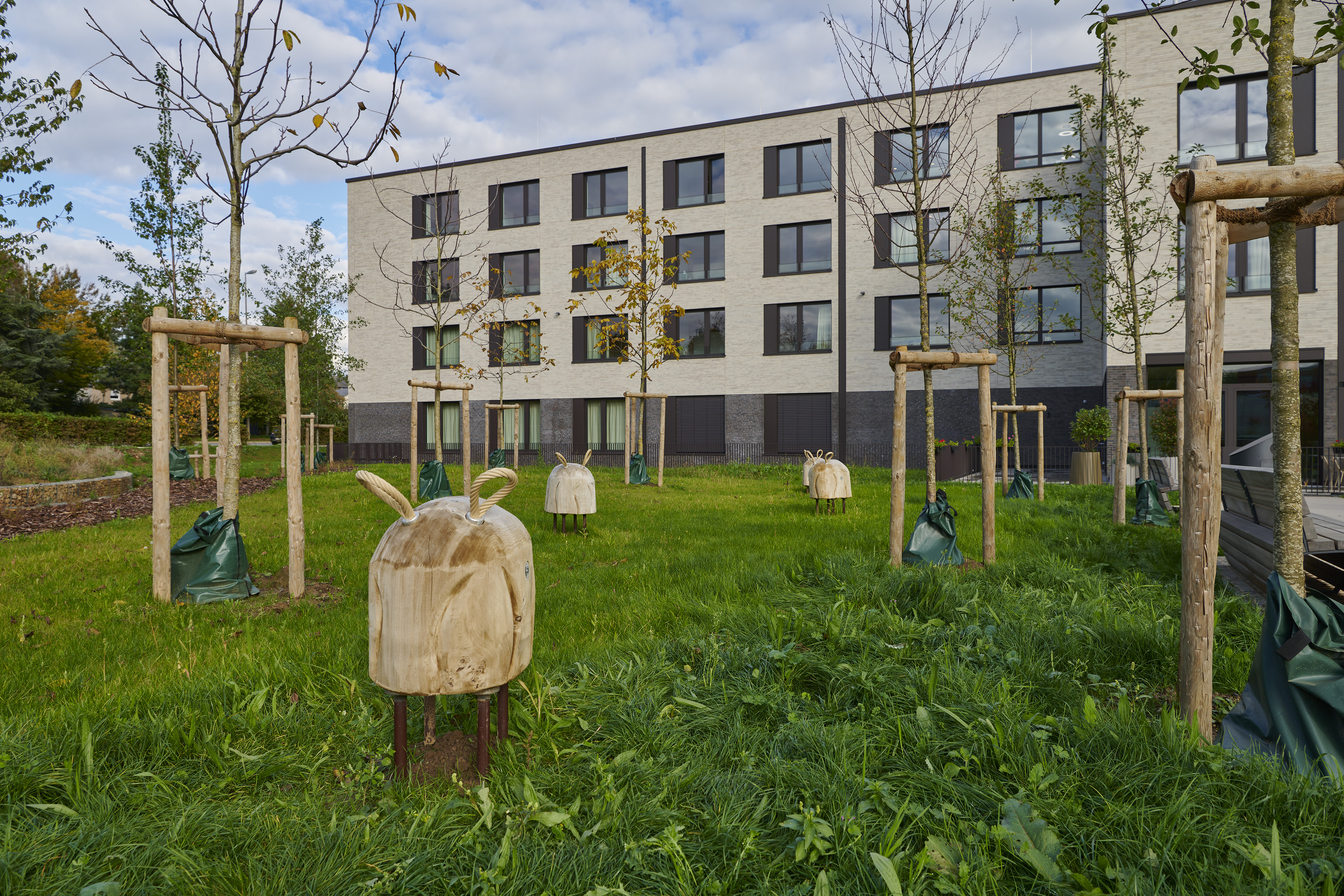 Fotografien Schulkomplex mit Kita und Retentionspark Wobrécken, Esch an der Alzette — Im Park sind Bänke, Lernspielzeuge und Bewegungsspielzeuge verteilt.