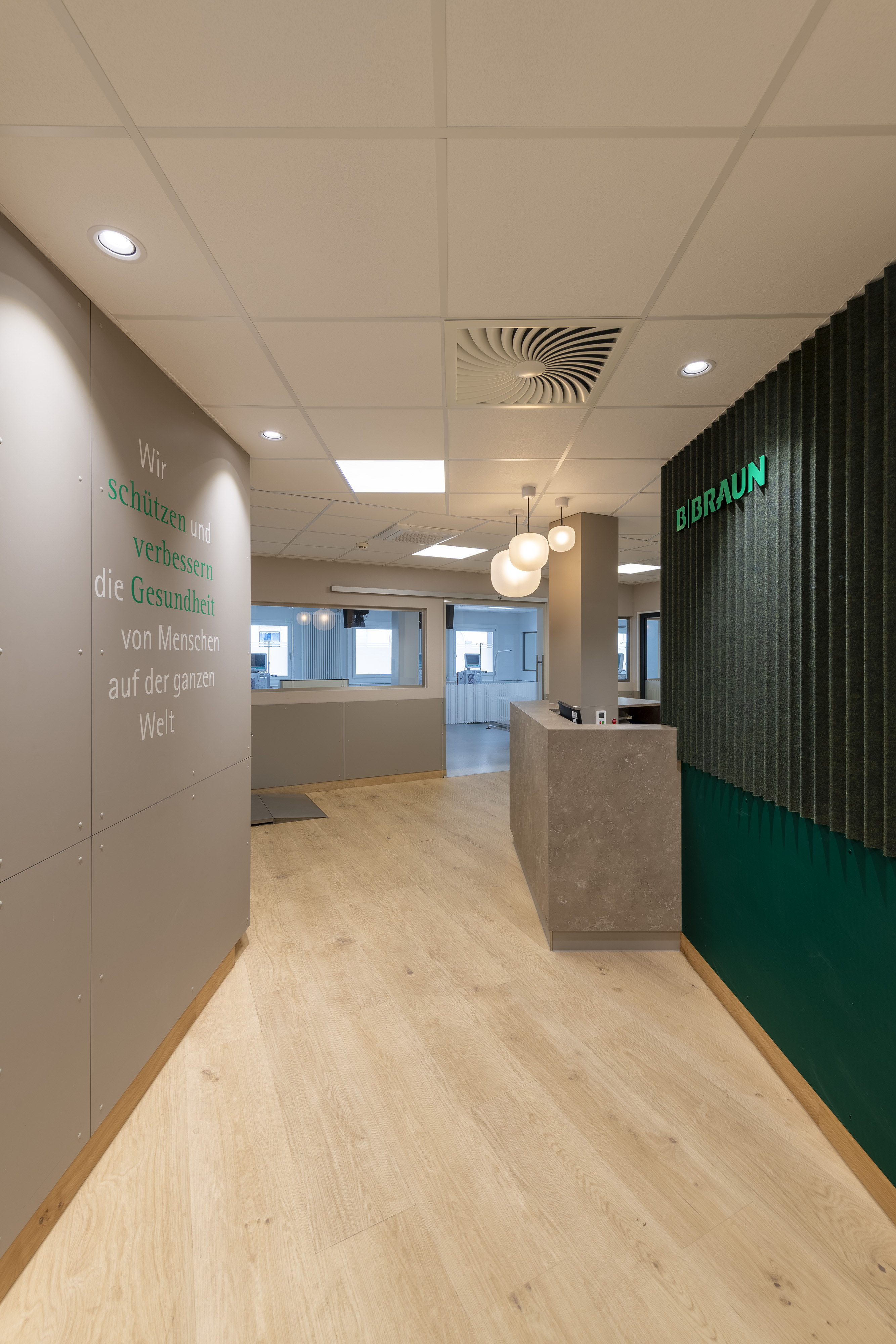 B. Braun Gesundheitszentrum Saarbrücken, Saarland — Eingangsflur mit Leitspruch an der Wand und grüner Lamellenwand am Empfang