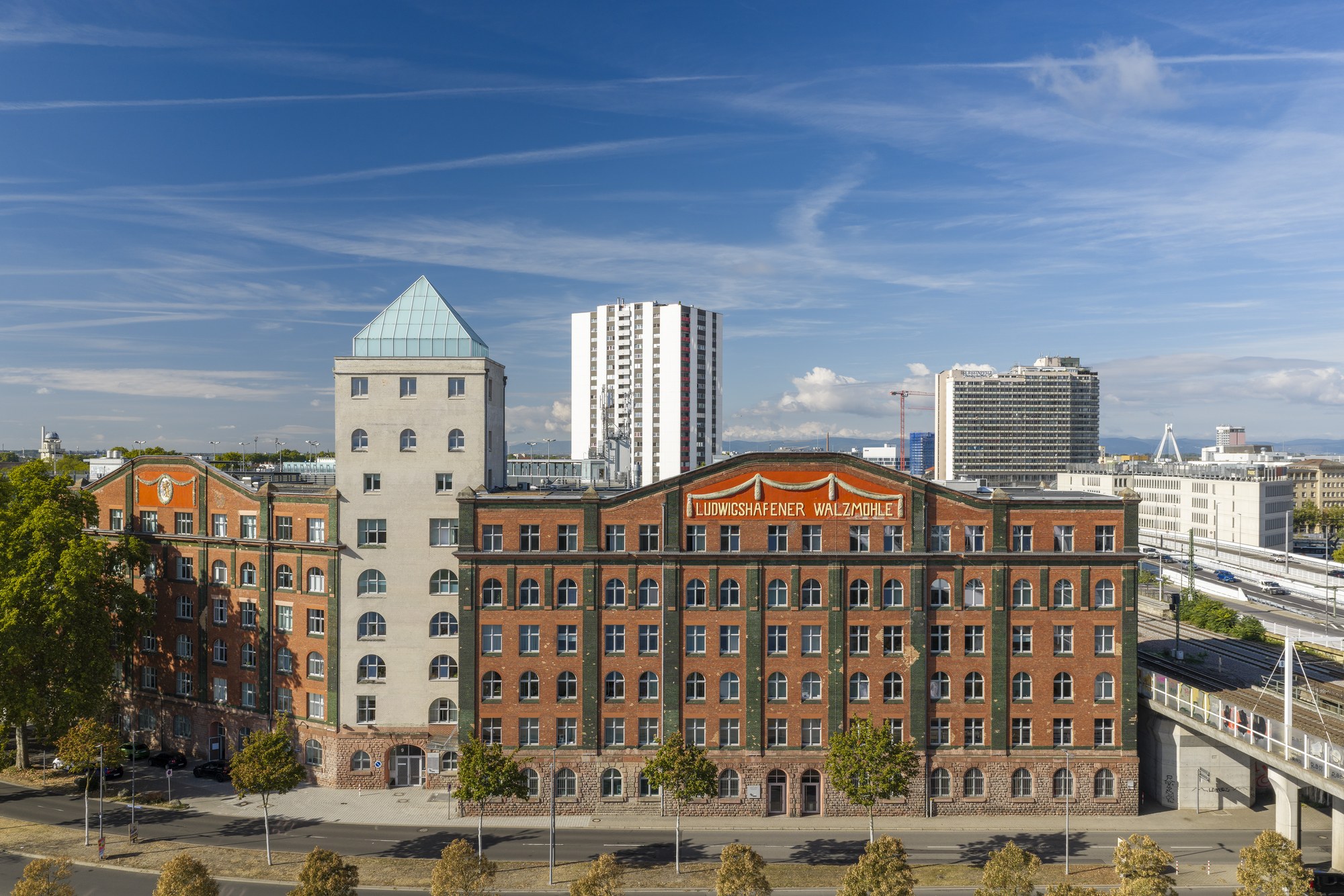 Ludwigshafener Walzmühle — der Backsteinbau mit Schriftzug und hellem Wasserturm, dahinter die Hochhäuser der Innenstadt