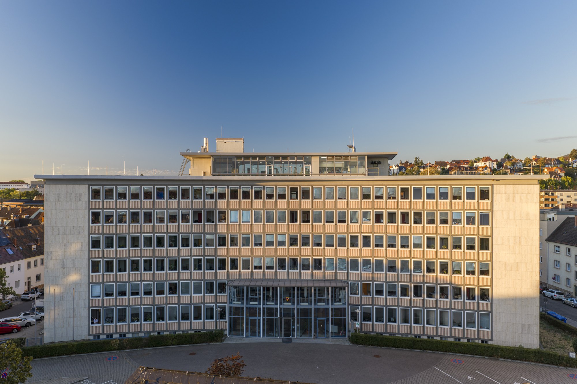 Bezirksregierungsgebäude, Neustadt an der Weinstraße — die konkav geschwungene Rasterfassade im Morgenlicht, obenauf der verglaste Dachaufsatz