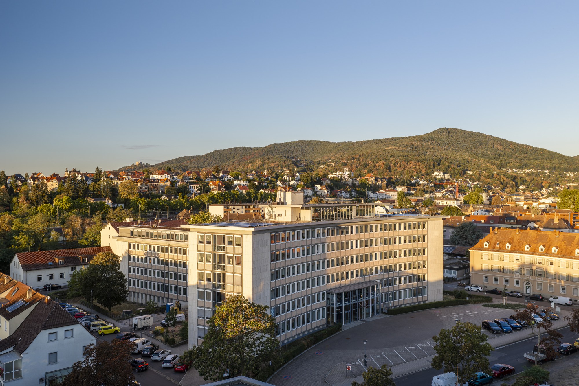 Bezirksregierungsgebäude, Neustadt an der Weinstraße — Schrägansicht der Vierflügelanlage, dahinter die bewaldete Haardt