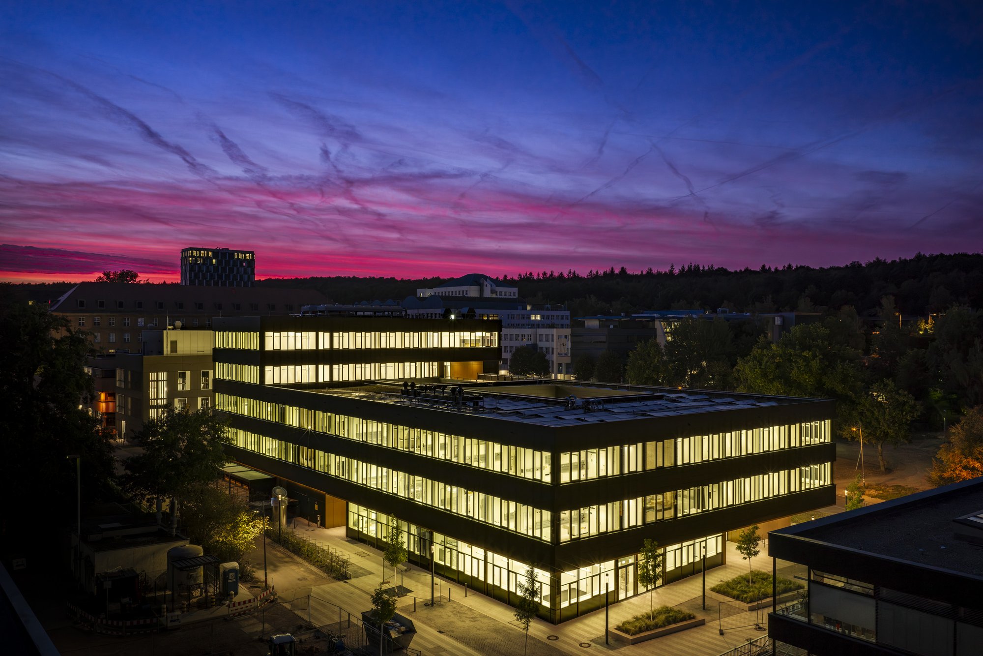 Architekturfotografie Zentrum für Biophysik ZBP, Saarbrücken — Nachtansicht von oben, das durchleuchtete Gebäude vor dunkelblauem Himmel