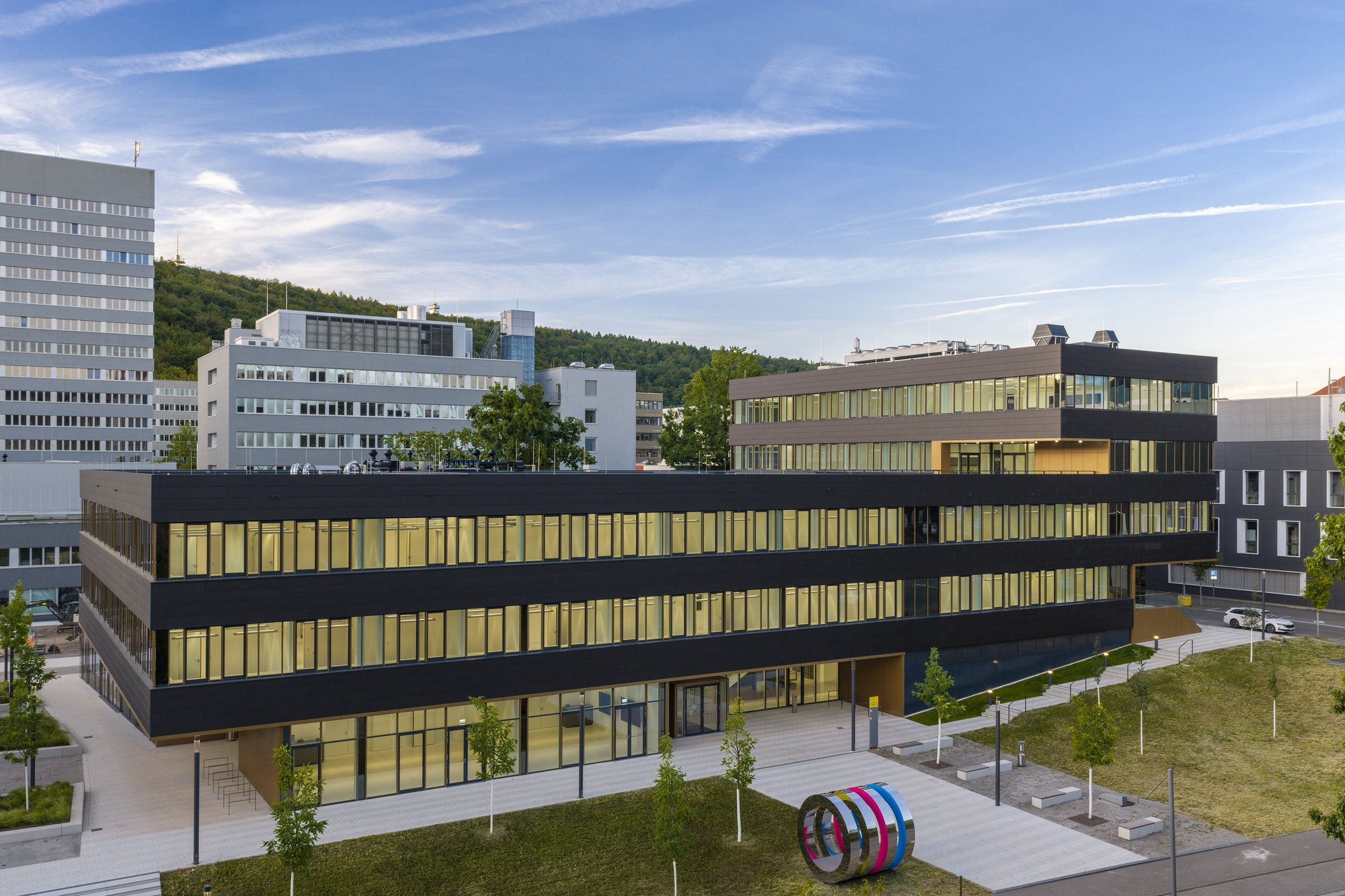 Architekturfotografie Zentrum für Biophysik ZBP, Saarbrücken — Erhöhte Gesamtansicht am Morgen, im Vordergrund die farbige Ringskulptur auf dem Vorplatz