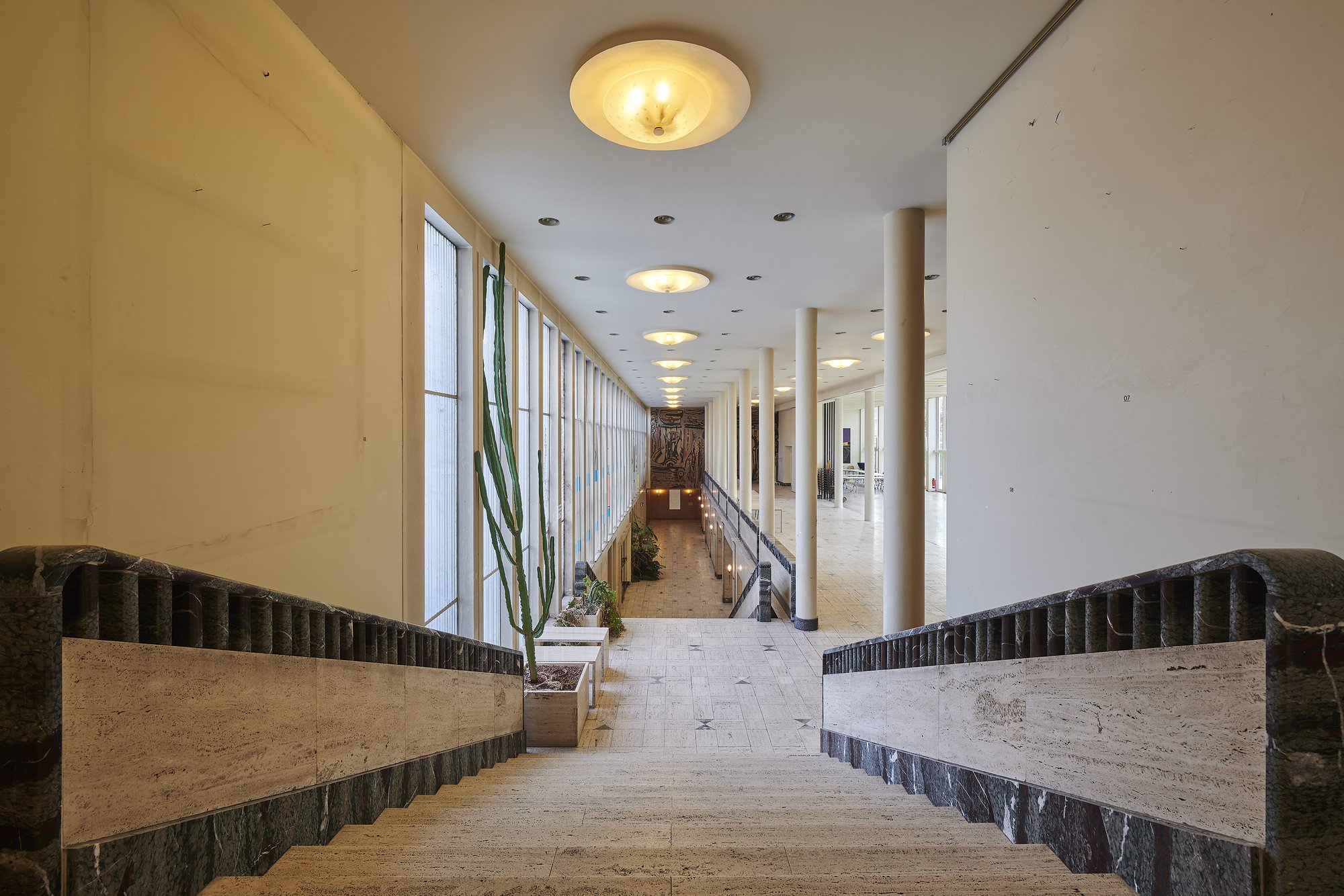 Ehemalige Französische Botschaft, Saarbrücken, Saarland — Ehrenhalle mit Pflanztrögen und Deckenleuchten, Blick zur Treppe