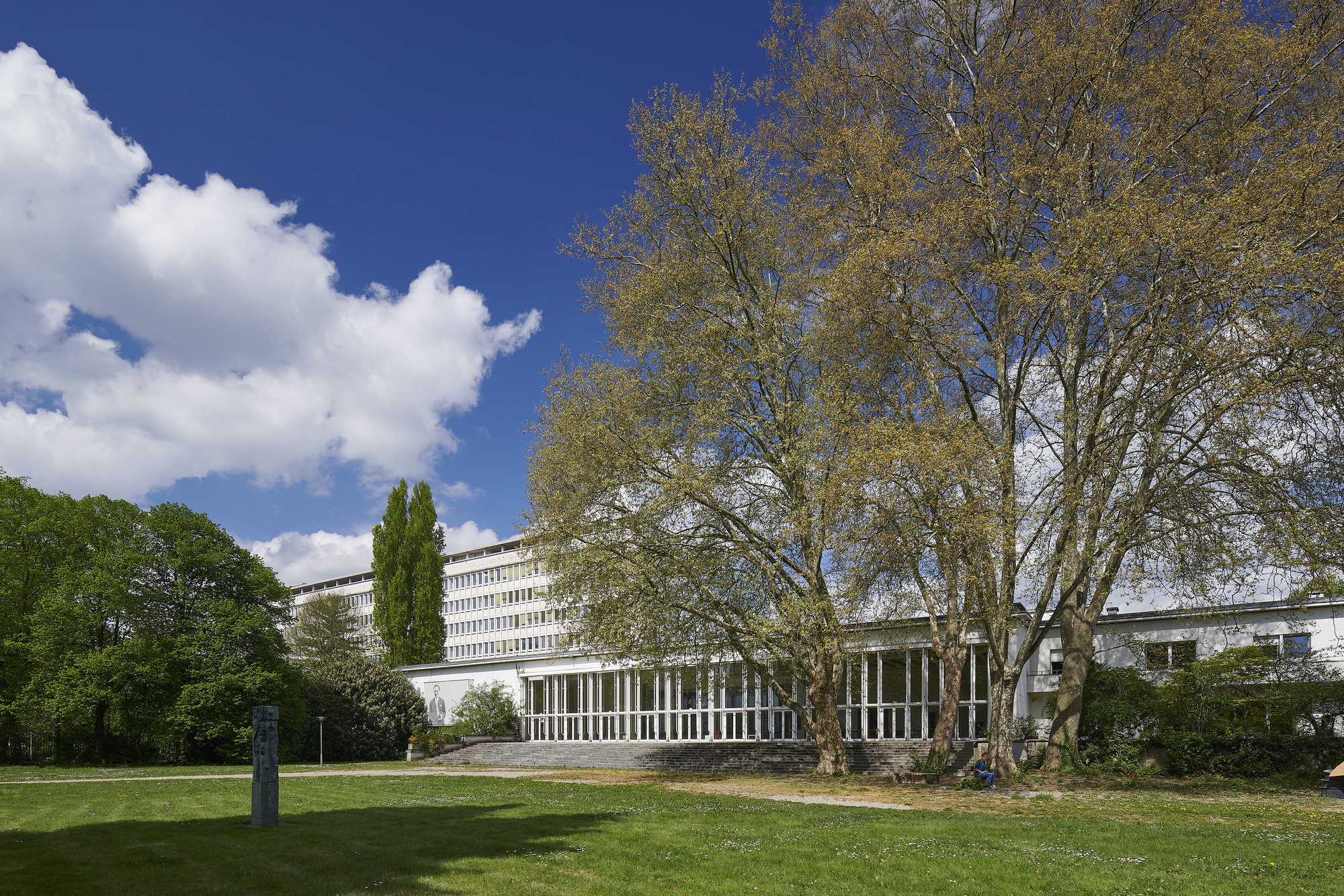 Ehemalige Französische Botschaft, Saarbrücken, Saarland — Blick über den Park auf den verglasten Flachbau, dahinter das Bürohochhaus