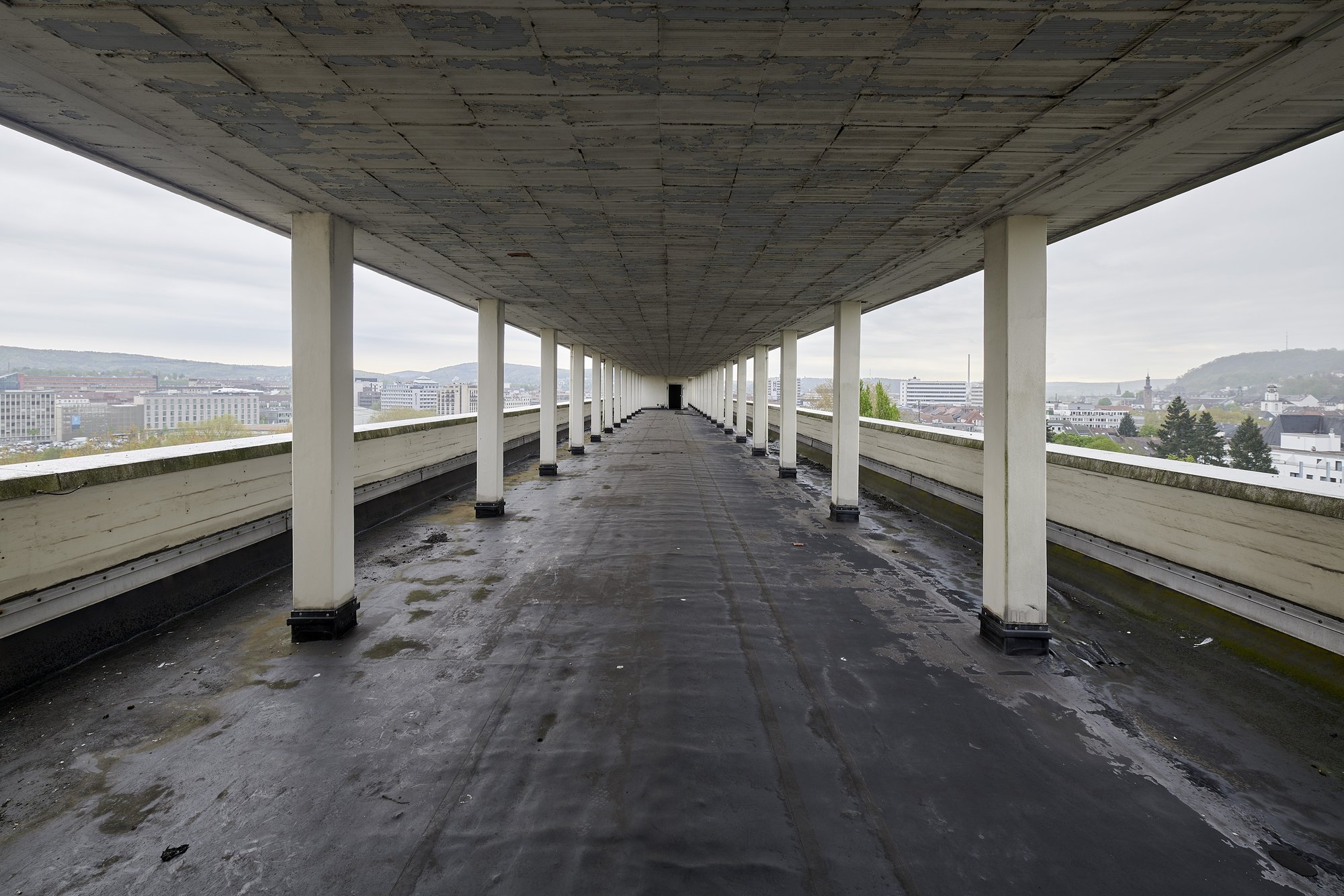 Ehemalige Französische Botschaft, Saarbrücken, Saarland — Stützenreihe auf der Dachterrasse, dahinter der Stadtrand