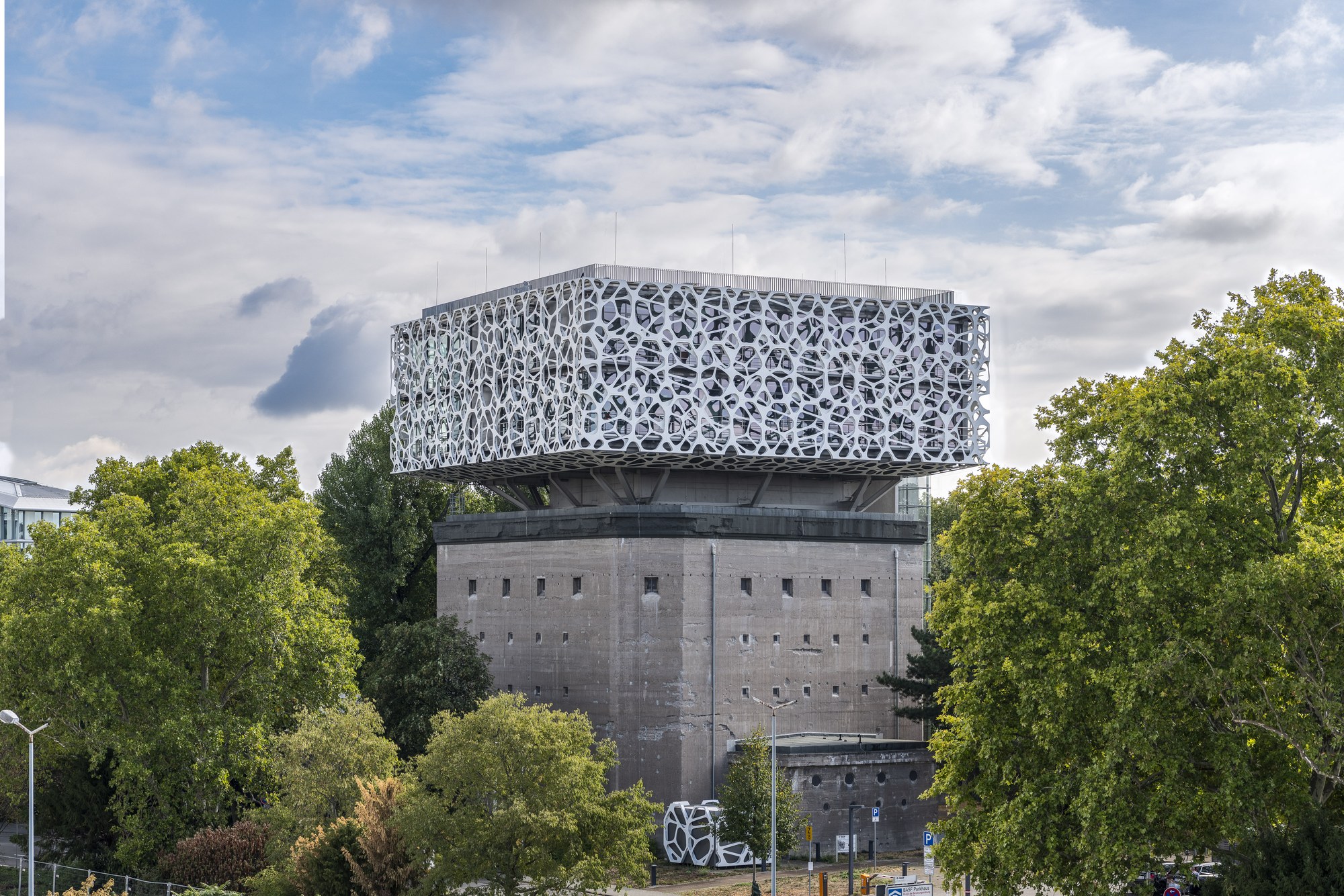 BASF Creation Center, Ludwigshafen am Rhein — der perforierte weiße Aufbau auf dem Betonbunker, gerahmt von Bäumen