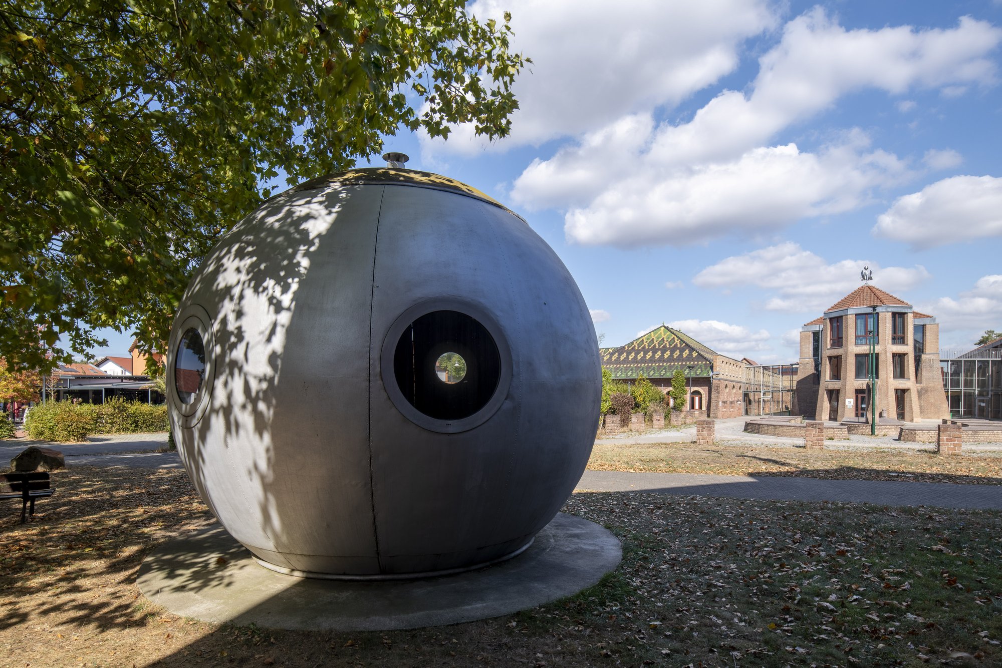Ludowici-Kugelhaus, Jockgrim — die metallene Wohnkugel auf ihrem Sockel, rechts das Ziegeleimuseum