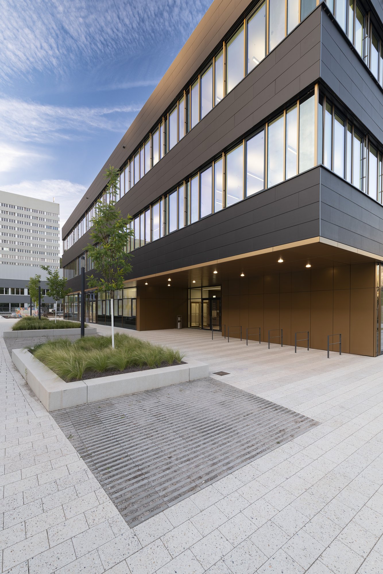 Architekturfotografie Zentrum für Biophysik ZBP, Saarbrücken — Eingangsseite mit bronzefarben verkleideter Vorzone und der Platzfläche aus hellem Werkstein