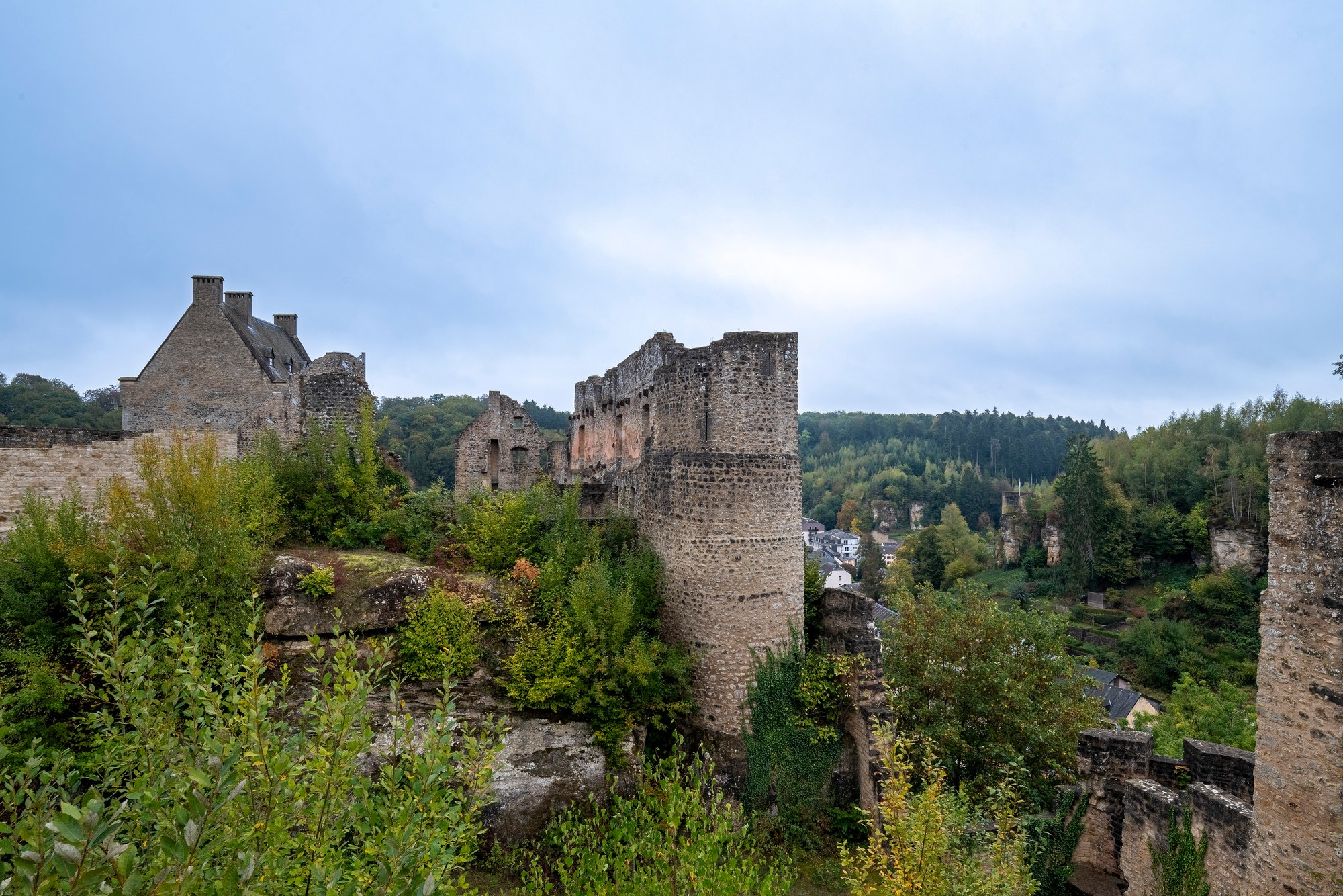 Architekturfotografie Burg Larochette — Ruinen und Rundturm auf dem Sandsteinfelsen, links das Criechinger Haus