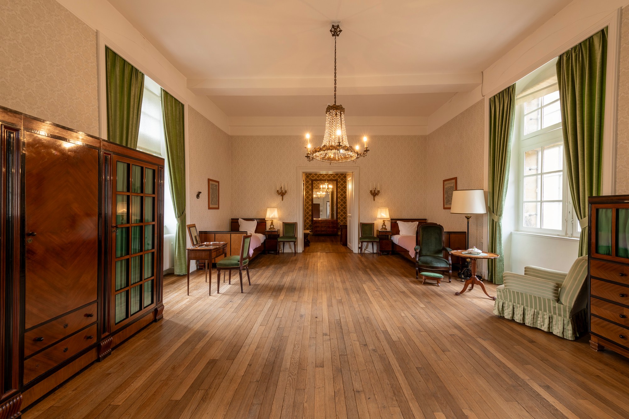 Architekturfotografie Renaissanceschloss Beaufort — Schlafzimmer mit Dielenboden, grünen Vorhängen, Jugendstil-Kommoden und Kronleuchter